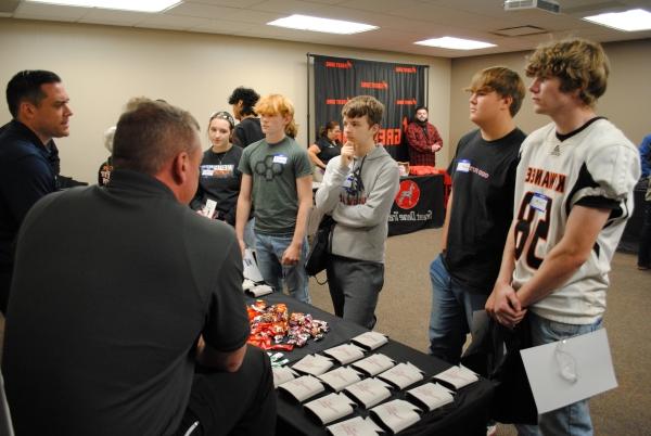 group of high school students at table talking to reps from manufacturing company